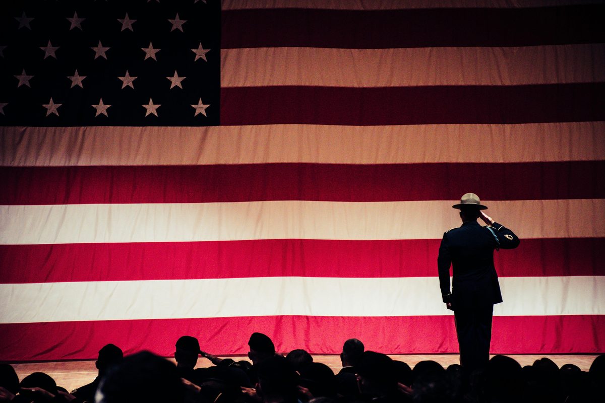 A soldier saluting before a large American flag
